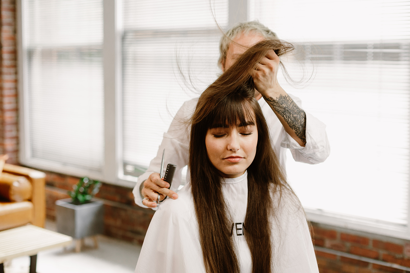 A women in a hair salon decides whether she should get bangs or let her hair grow out.